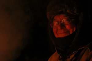Ken Weaver smiles as the glow of the fire warms his face at Duck Lake in Yellowknife, NWT.